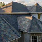 Mixed roofing materials on residential home showing combination of asphalt shingles and slate tiles