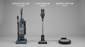 A golden retriever sitting on a wooden floor next to a pet hair vacuum.